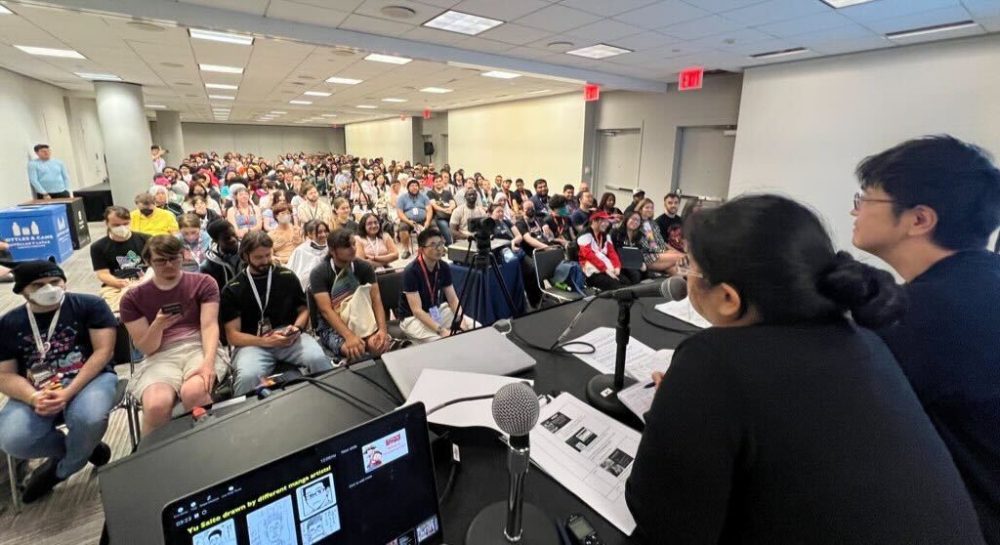 photo of panel room showing packed crowd as well as panel moderator and yu saito.